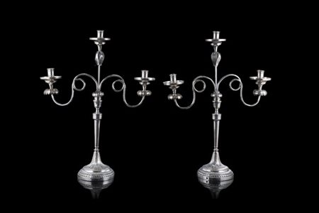 Coppia di candelabri in argento a tre fiamme. Basi circolari sbalzate e decorat