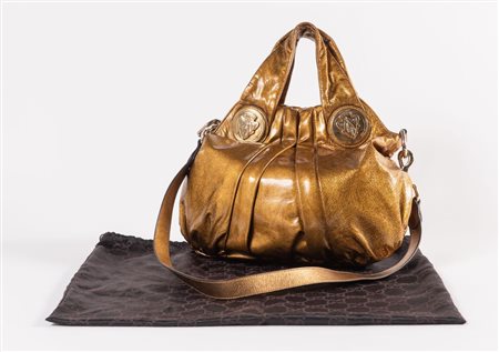 GUCCI Borsa a mano in pelle verniciata oro con dettagli e medaglioni con logo...