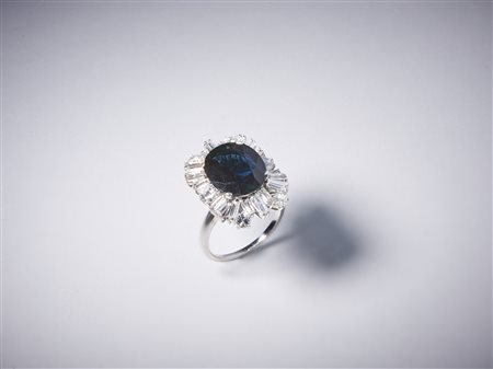  . - Anello artigianale in oro bianco 750/1000 con diamanti bianchi taglio a brillante per tot. 1,50 ct circa e diamanti bianchi taglio a baguette di 3,50 ct circa con zaffiro blu centrale 7,50 ct circa.