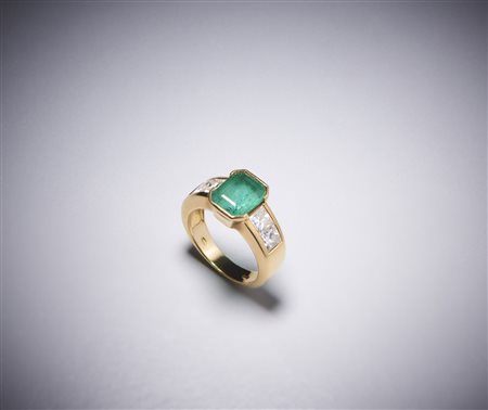  . - Un anello in oro giallo 750/1000 con smeraldo colombiano centrale ct 2,50 con contorno di diamanti bianchi  taglio princess, 1,30 ct.circa.