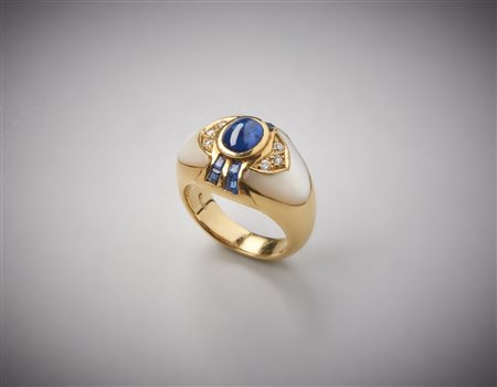  . - Anello in oro giallo 750/1000  e base di madreperla bianca con zaffiro centrale blu cabochon di circa 1,00 carati e zaffiri  blu laterali taglio carrè e diamanti bianchi taglio a brillante ct.0,14.