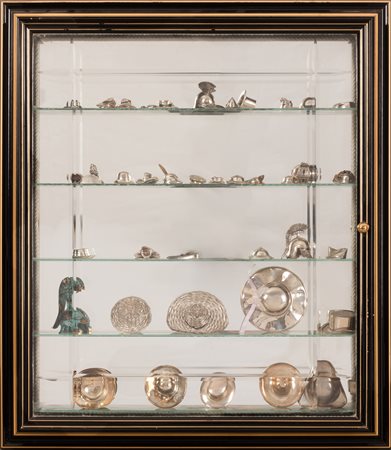  
Teca in vetro contenente miniature di cappelli in metallo e argento 
 