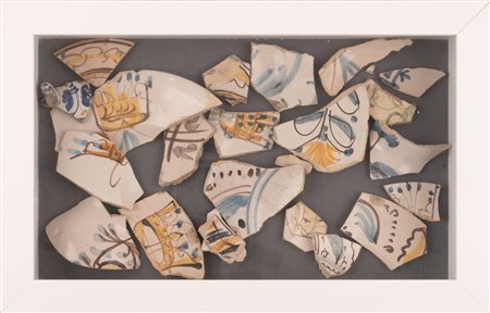  
Collezione di frammenti di maioliche di Castelli  (prevalentemente piatti) con decorazione in stile compendiario e tardo compendiario contenuta in moderna teca lignea bianca con vetro. 
 la teca cm 47x30