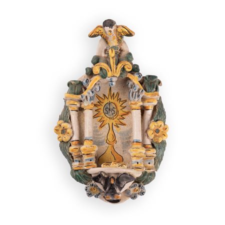 Manifattura di Cerreto Sannita attiva nel XVIII secolo ( - ) 
Acquasantiera in maiolica con decori a rilievo ed il simbolo eucaristico (IHS) nell'edicola centrale. 
 cm 26x17,5