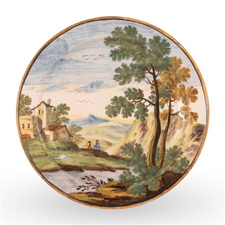 Manifattura castellana del XVIII secolo ( - ) 
Piatto in maiolica decorato in policromia con paesaggio alberato, fiume, personaggi e case 
 Ø cm 23,5