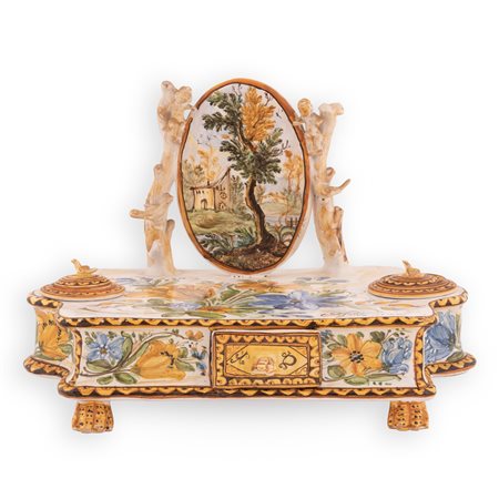 Manifattura Antonio de Simone, Castelli XX secolo ( - ) 
Calamaio in maiolica a fondo bianco decorato in policromia. Al centro medaglione ovale con paesaggio sorretto da putti. 
 cm 26x38x23