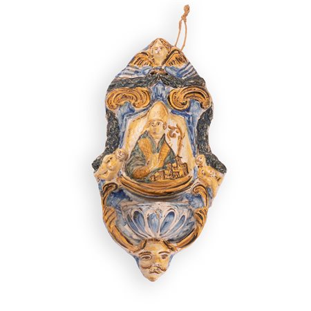 Manifattura castellana della seconda metà del XVIII secolo ( - ) 
Acquasantiera in maiolica decorata con elementi a rilievo ed al centro, con l'effigie di un Santo Vescovo in atto benedicente (Sant'Emidio?) 
 cm 28x16