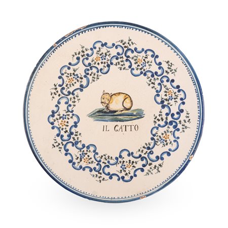 Manifattura abruzzese attiva tra il tardo XIX ed i primi del  XX secolo. ( - ) 
Tagliere in maiolica decorato con la figura di un gatto racchiusa in una riserva circolare, composto da elementi floreali e volute 
 Ø cm 35,5