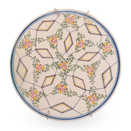 Manifattura abruzzese del XX secolo ( - ) 
Tagliere in maiolica decorato con elementi geometrici e floreali 
 Ø cm 30