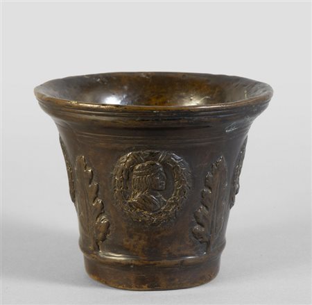 Antico mortaio in bronzo con profili virili, 