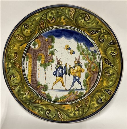 Piatto in ceramica decorato nel cavetto da scena all'aperto e volute lungo la t