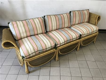 Divano a tre posti in vimini verniciato color oro, cuscini in tessuto a righe.