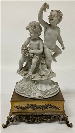 Gruppo in biscuit raffigurante amorini giocosi con fiori, base in metallo dorat