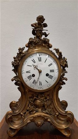 :  PAUTASSO. Pendola in bronzo dorato con cassa di gusto rocaille, quadrante in smalto bianco a numeri romani per le ore e arabi per i minuti. Movimento a due treni con suoneria delle ore e mezze. Ultimo quarto del secolo XIX (h.cm 43) (difetti) 