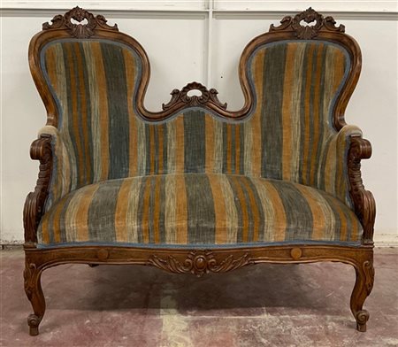 Divano di forma mossa a due posti in noce intagliato a foglie e volute, rivesti