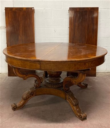 Tavolo allungabile di forma tonda lastronato in noce poggiante su gamba central