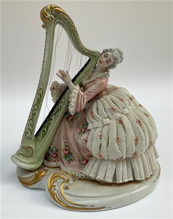 Scultura in porcellana policroma raffigurante una suonatrice di arpa in abiti s
