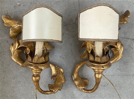 Coppia di applique a una luce in legno intagliato e dorato a volute fogliate (c