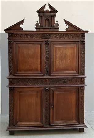 Credenza a due corpi in legno intagliato a girali di foglie tra mascheroni, sul
