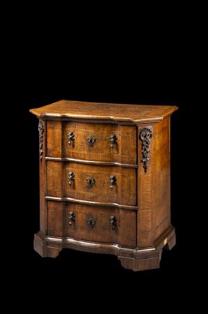 Comodino con piano di forma sagomata e fronte mosso a tre cassetti in noce e ra