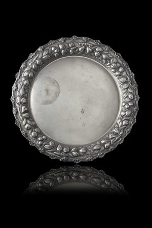 Vassoio circolare in argento con bordo decorato da frutti e foglie a rilievo. T