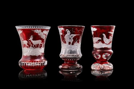 Manifattura di Boemia, fine secolo XIX. Gruppo di tre calici in vetro rosso inc