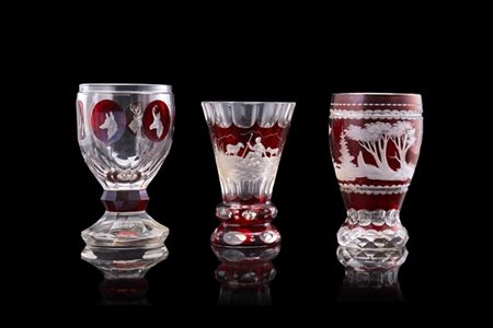 Manifattura di Boemia, fine secolo XIX. Gruppo di tre calici in vetro rosso inc