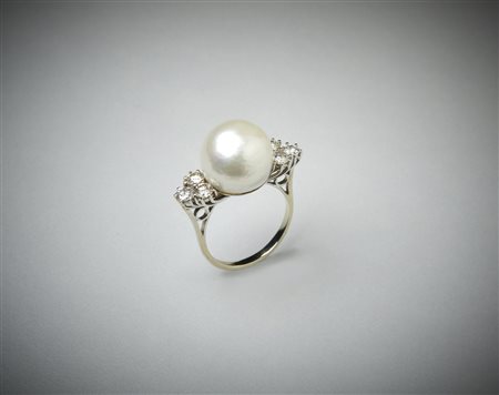  . - Anello con perla  bianca coltivata e sei diamanti laterali taglio a brillante di circa 1 ct. totale.