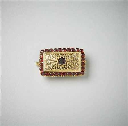  . - Spilla in oro giallo 750/1000  traforata con granati arancioni. .