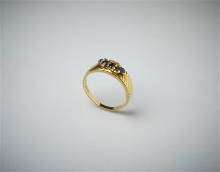  . - Anello in oro giallo 750/1000  a fascetta con piccoli quattro zaffiri blu di 0.35 ct. e due piccoli diamanti. .