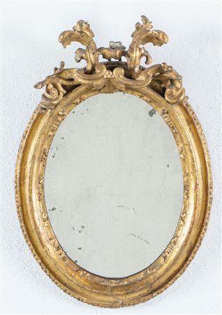 Piccola specchiera in legno intagliato e dorato. Reca cimasa in legno con...