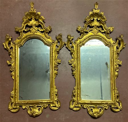 Coppia di specchiere in legno intagliato e dorato decorato da fregi a volute di