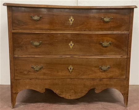 Cassettone in noce con fronte mosso a tre cassetti, grembiale e piano sagomato.