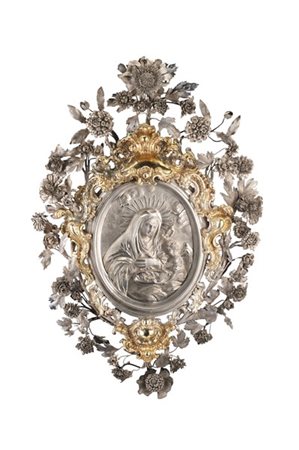 Cornice votiva in argento sbalzato e decorato a volute e fiori centrata da plac