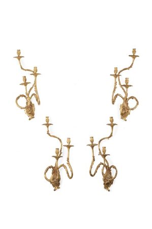 Gruppo di quattro applique a tre fiamme in legno intagliato e dorato, bracci sa