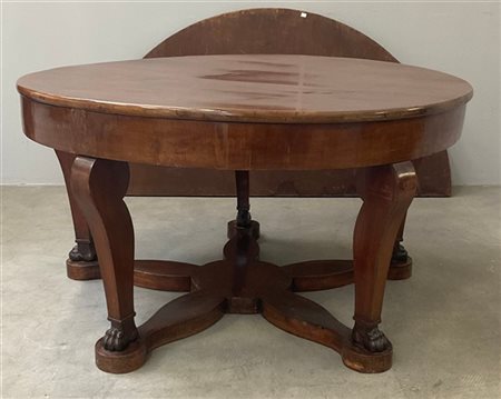 Tavolo con piano circolare, gambe mosse terminanti a piede ferino riunite da tr