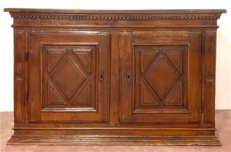 Antica credenza in noce a due ante pannellate e riquadrate, dentellatura sottop