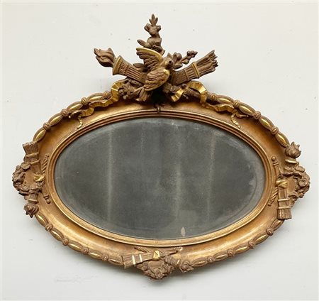 Specchio di forma ovale in legno e pastiglia dorata decorata a rilievo nella ci