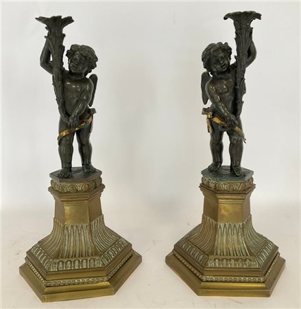 Scultore del secolo XIX. Coppia di putti reggitorcia a cornucopia in bronzo bru