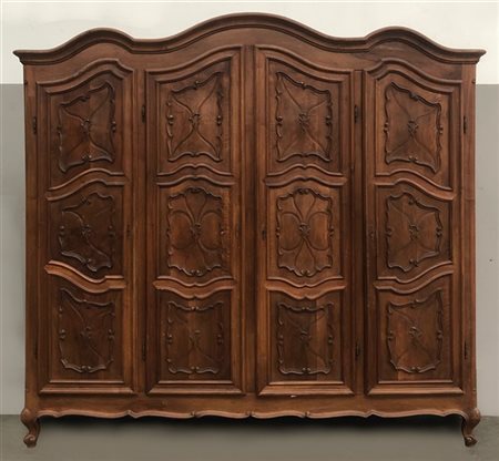 Armadio noce di forma mossa a quattro ante pannellate intagliate a ragnatela a