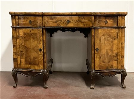 Scrivania da centro lastronata in radica di noce mossa sul fronte e sui fianchi