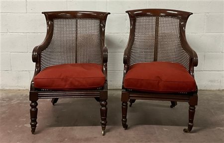 Coppia di poltrone di forma mossa lastronate in mogano, braccioli terminanti a