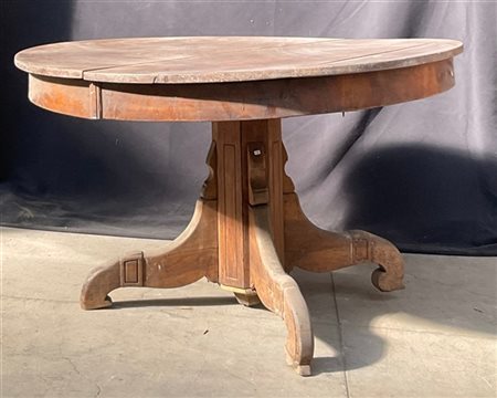 Tavolo tondo allungabile retto da un fusto su gambe mosse. (d cm 125, h cm 72)