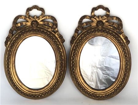 Coppia di specchiere in legno e stucco dorato di forma ovale con bordura perlin