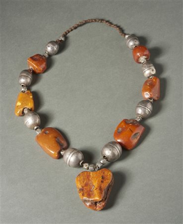  Arte Tibetana - Tibet. 
Collana in ambra grezza, argento e fibre. 
Con consunzioni e segni d'uso. .