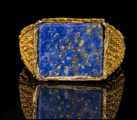 A LARGE FATIMID GOLD GRANULATED RING WITH A RECTANGULAR BEZEL TABLE SET WITH A LAPIS LAZULI. 