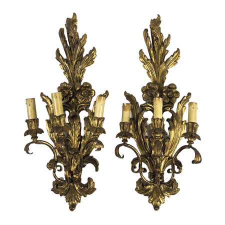 Coppia di appliques in legno e metallo dorato, a tre luci intagliate a motivi...