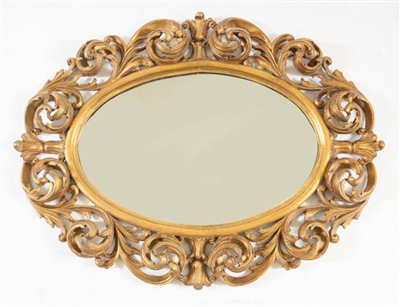 Specchiera ovale in legno intagliato e dorato. Di gusto ottocentesco, ma...