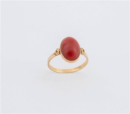 Anello in oro giallo 18K, centrato da cabochon ovale di corallo rosso...
