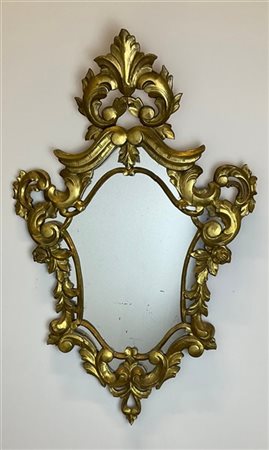 Specchiera in legno intagliato, traforato e dorato, sagomata con cornice a volu